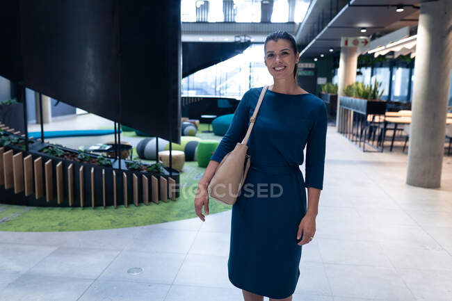 Portrait of a caucasian businesswoman smiling while standing at modern office. business and office concept — Stock Photo
