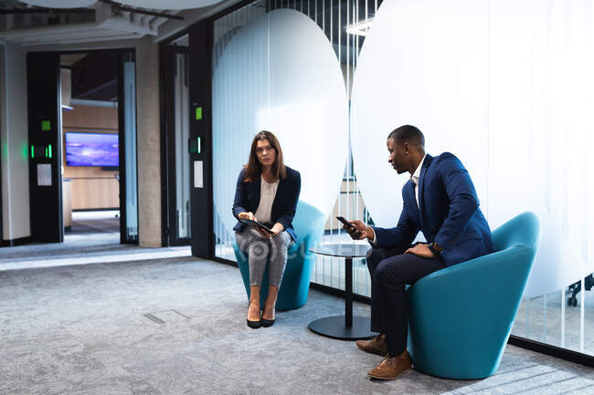 Diverso hombre de negocios y mujer de negocios discutiendo juntos mientras están sentados en la oficina moderna. concepto de negocio y oficina - foto de stock