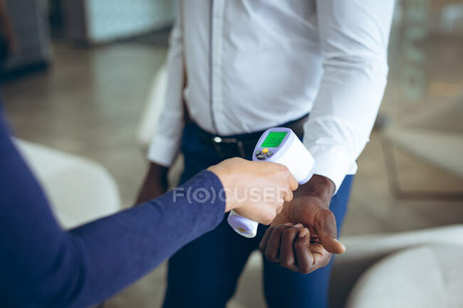 Two business colleagues taking temperature. work at a modern office during covid 19 coronavirus pandemic. — Stock Photo