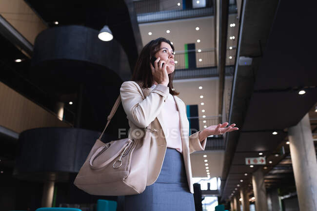 Kaukasische Geschäftsfrau, die im modernen Büro auf einem Smartphone spricht. Geschäfts- und Bürokonzept — Stockfoto