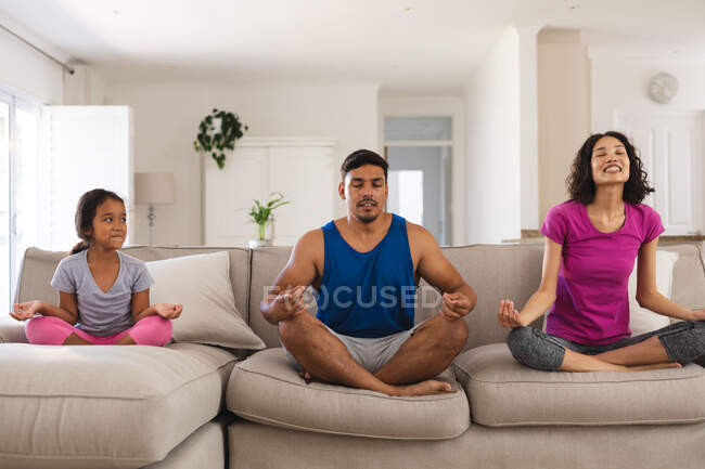 Щаслива його дочка і батьки практикують йогу, сидячи на дивані у вітальні. вдома в ізоляції під час карантину . — стокове фото