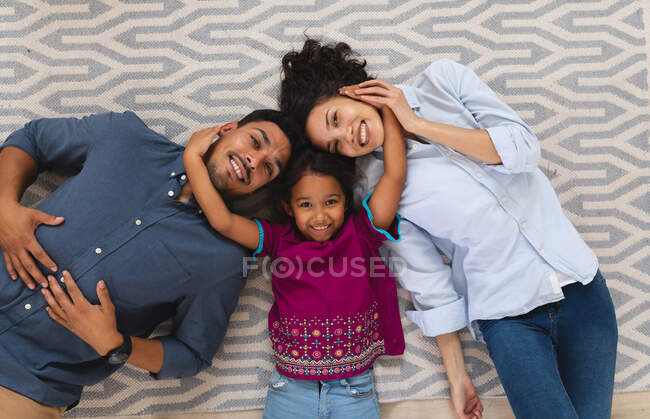 Портрет усміхненої шикарної матері, батька і доньки, які лежать на підлозі, обіймаючи. вдома в ізоляції під час карантину.. — стокове фото