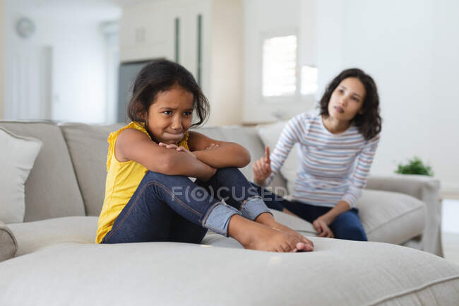 Traurige hispanische Tochter, die auf der Couch sitzt und von der Mutter wegerzählt wird. Familie verbringt Zeit zusammen zu Hause. Anzeige — Stockfoto
