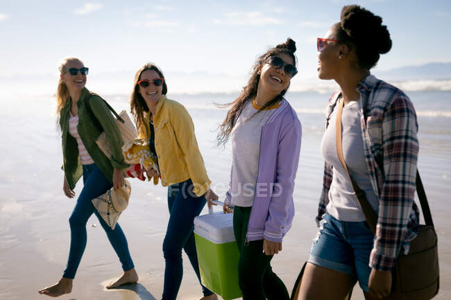 Счастливая группа разнообразных подруг, веселящихся, гуляющих по пляжу и смеющихся. отдых, свобода и досуг на открытом воздухе. — стоковое фото