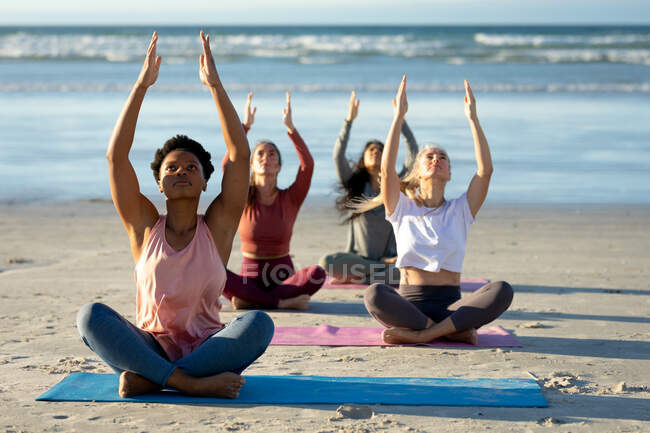 Group of diverse female friends practicing yoga, meditating at the beach. healthy active lifestyle, outdoor fitness and wellbeing. — Stock Photo