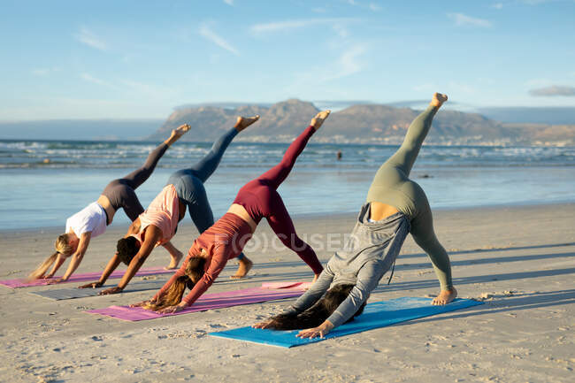 Gruppe verschiedener Freundinnen, die Yoga praktizieren, sich am Strand dehnen. gesunder aktiver Lebensstil, Fitness und Wohlbefinden im Freien. — Stockfoto