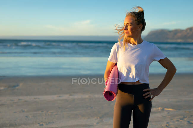 Portrait de femme caucasienne pratiquant le yoga, debout à la plage et faisant une pause. mode de vie sain et actif, forme physique extérieure et bien-être. — Photo de stock