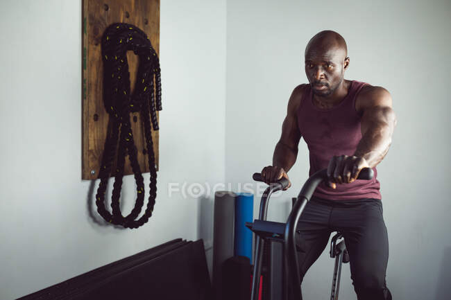 Подходит африканский американец тренирующийся в тренажерном зале с помощью гребного тренажера. здоровый активный образ жизни, кросс тренировки для фитнеса. — стоковое фото