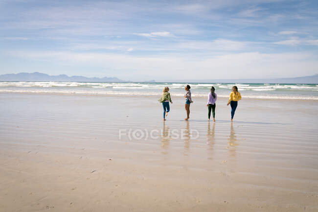 Fröhliche Gruppe unterschiedlicher Freundinnen, die Spaß haben, am Strand spazieren gehen und lachen. Urlaub, Freiheit und Freizeit im Freien. — Stockfoto