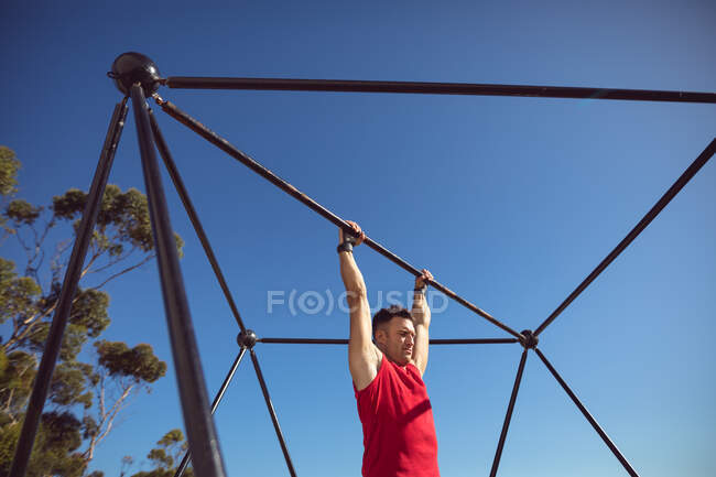 Homem musculoso caucasiano pendurado em quadro de exercício ao ar livre. estilo de vida ativo saudável, treinamento cruzado para fitness. — Fotografia de Stock