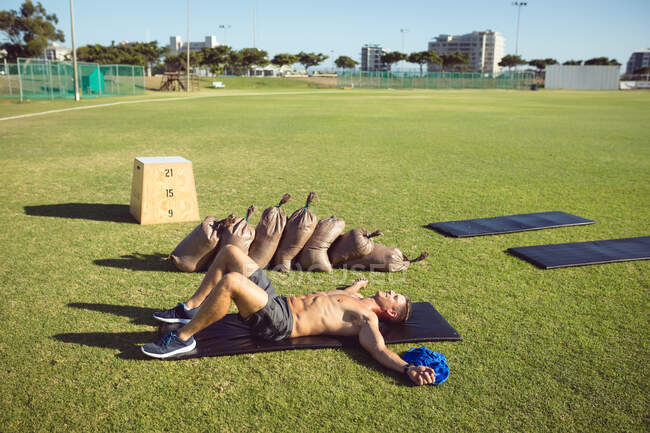 Homem musculoso caucasiano exercitando ao ar livre, fazendo prancha lateral. estilo de vida ativo saudável, treinamento cruzado para fitness. — Fotografia de Stock