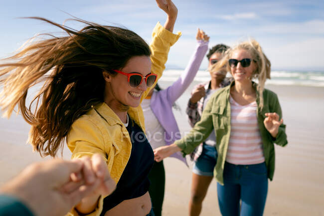 Heureux groupe de diverses amies qui s'amusent, marchent le long de la plage en se tenant la main et en riant. vacances, liberté et loisirs en plein air. — Photo de stock
