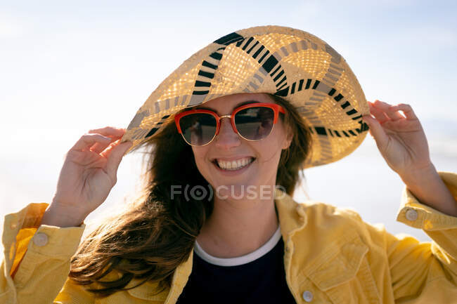 Retrato de mujer caucásica feliz con sombrero que se divierte en la playa sonriendo. vacaciones, libertad y tiempo libre al aire libre. - foto de stock