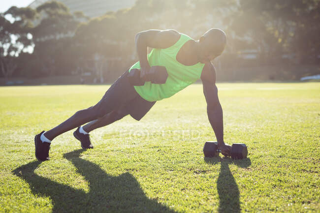 Африканський америкійський м'язовий чоловік тренувався на відкритому повітрі з тупоголовими дзвінками. Здоровий активний спосіб життя, перехресна підготовка до фітнесу — стокове фото
