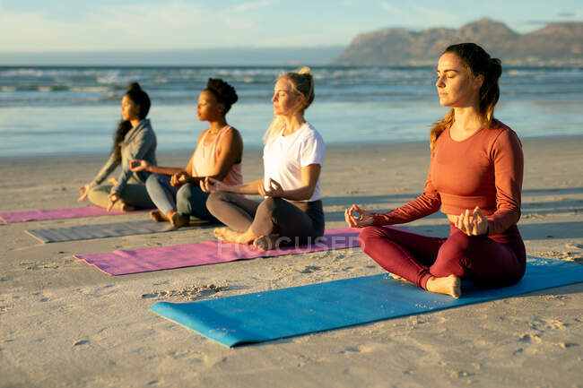 Gruppe verschiedener Freundinnen, die Yoga praktizieren und am Strand meditieren. gesunder aktiver Lebensstil, Fitness und Wohlbefinden im Freien. — Stockfoto