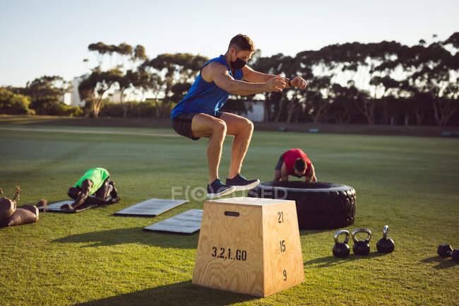 Fit caucasian man exercising outdoors jumping on to box. healthy active lifestyle, cross training for fitness. — Stock Photo