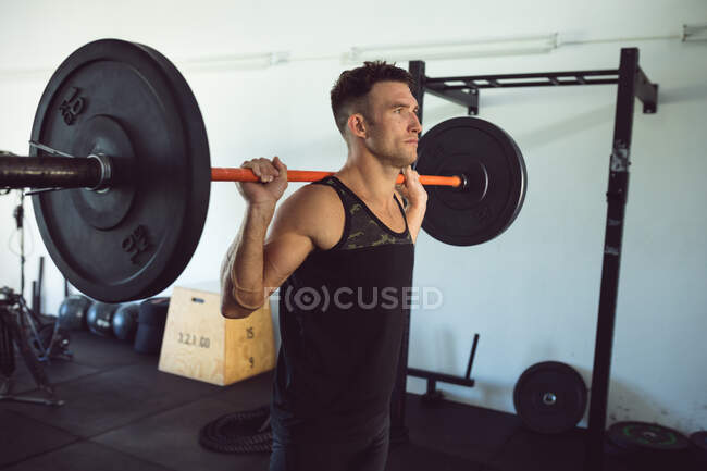 Fitter Kaukasier, der im Fitnessstudio trainiert und Gewichte auf der Langhantel stemmt. gesunder aktiver Lebensstil, Crosstraining für Fitness. — Stockfoto