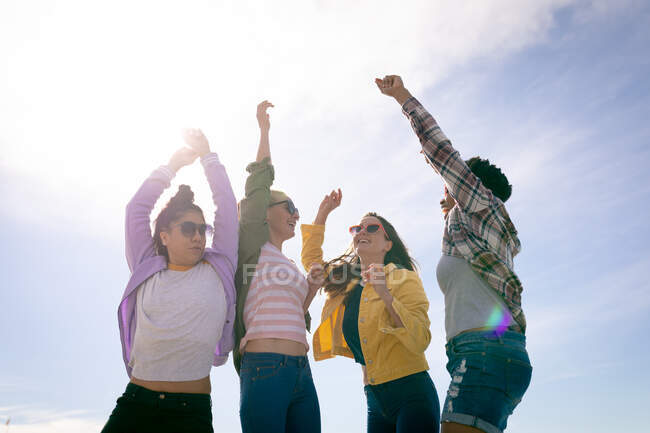 Happy group of diverse female friends having fun, with hands in the air. holiday, freedom and leisure time outdoors. — Stock Photo