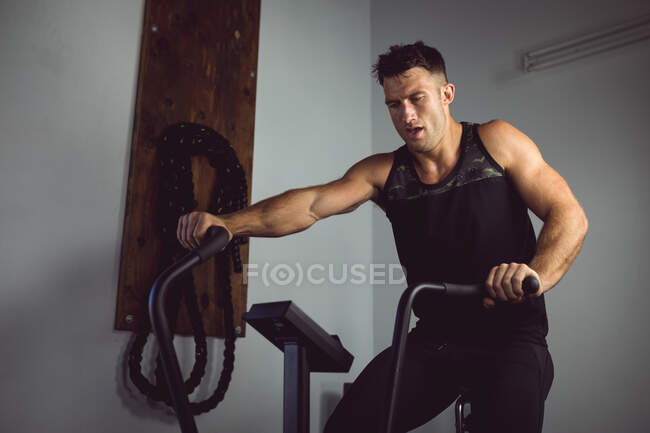 Ajuste homem caucasiano exercitando no ginásio, usando cross trainer. estilo de vida ativo saudável, treinamento cruzado para fitness. — Fotografia de Stock
