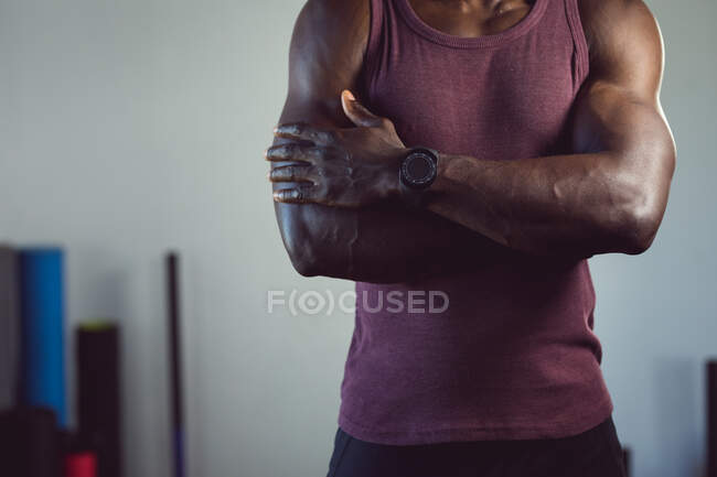 Sezione centrale dell'uomo afroamericano in forma che si allena in palestra, in piedi con le braccia incrociate. sano stile di vita attivo, cross training per il fitness. — Foto stock