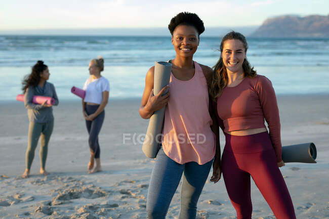 Portrait of two women practicing yoga, standing at the beach taking break. healthy active lifestyle, outdoor fitness and wellbeing. — Stock Photo