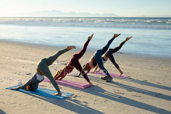 Група різноманітних друзів-жінок, які практикують йогу, тягнеться на пляжі. здоровий активний спосіб життя, фітнес на відкритому повітрі та благополуччя . — стокове фото