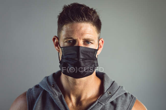 Portrait of fit caucasian man wearing face mask at gym. healthy active lifestyle, cross training for fitness during coronavirus covid 19 pandemic — Stock Photo