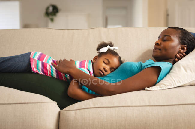 Glückliche afrikanisch-amerikanische Mutter und Tochter entspannt auf dem Sofa liegend. Familie verbringt Zeit zu Hause. — Stockfoto