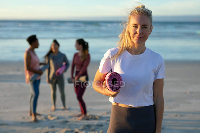Retrato de una mujer caucásica practicando yoga, de pie en la playa tomando un descanso. estilo de vida activo saludable, fitness al aire libre y bienestar. - foto de stock