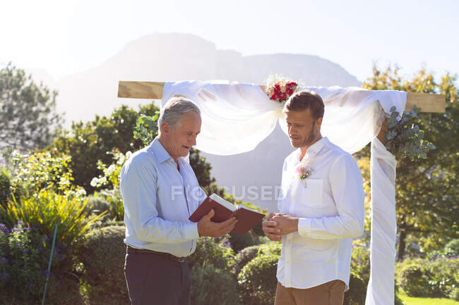 Sposo caucasico sposarsi e parlare con officiante di nozze. matrimonio estivo, matrimonio, amore e concetto di celebrazione. — Foto stock