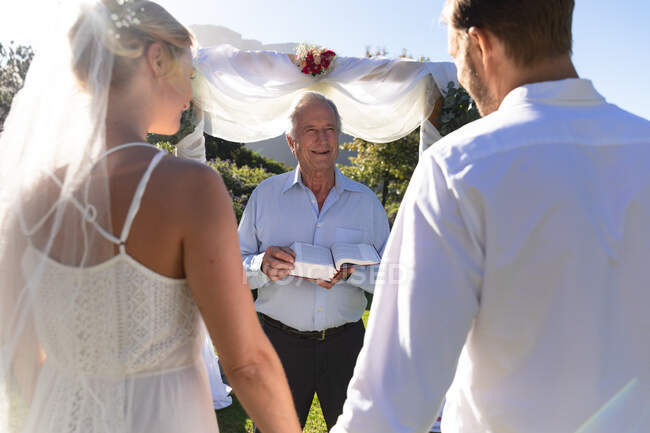Felici sposi caucasici che si sposano tenendosi per mano giurando. matrimonio estivo, matrimonio, amore e concetto di celebrazione. — Foto stock
