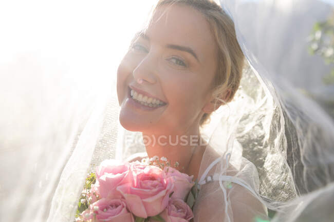 Retrato de la feliz novia caucásica casándose sosteniendo flores. boda de verano, matrimonio, amor y concepto de celebración. - foto de stock