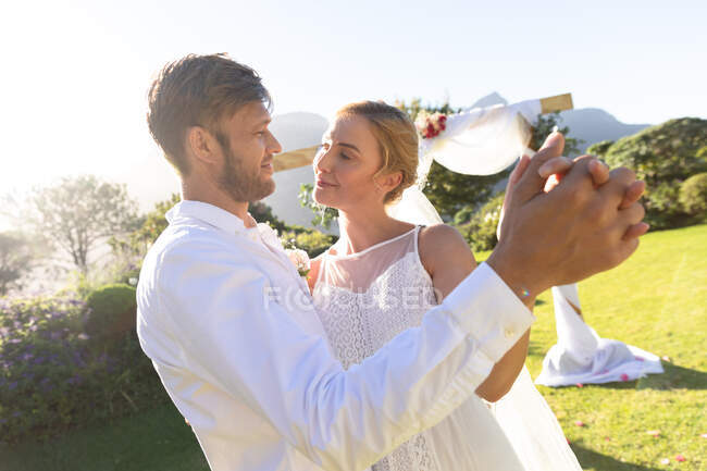 Счастливая кавказская невеста и жених женятся и держатся за руки. летняя свадьба, свадьба, любовь и праздник. — стоковое фото