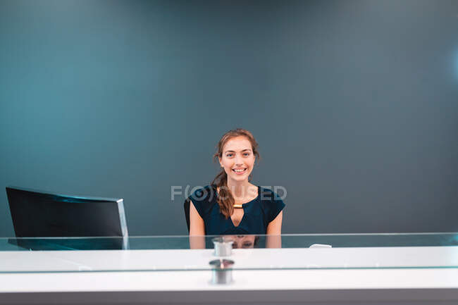 Portrait d'une femme d'affaires caucasienne souriante et assise à une table en verre. travailler dans une entreprise créative indépendante. — Photo de stock