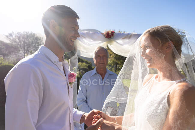 Noiva caucasiana feliz e noivo se casar de mãos dadas jurando. casamento de verão, casamento, amor e celebração conceito. — Fotografia de Stock