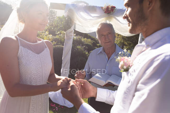 Feliz novia caucásica y novio casarse tomados de la mano jurando. boda de verano, matrimonio, amor y concepto de celebración. - foto de stock