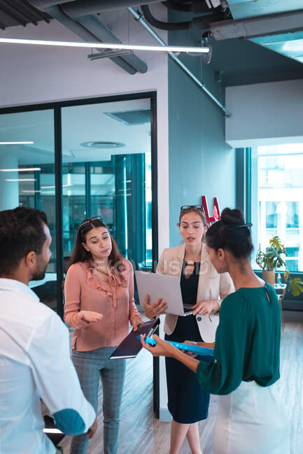 Gruppe verschiedener Geschäftsleute diskutiert zusammen und hält Dokumente und Laptop in der Hand. Arbeit in einem modernen Büro. — Stockfoto