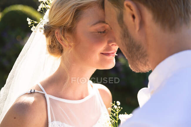 Glückliche kaukasische Braut und Bräutigam, die heiraten, berühren ihre Stirn. Sommerhochzeit, Ehe, Liebe und Festkonzept. — Stockfoto