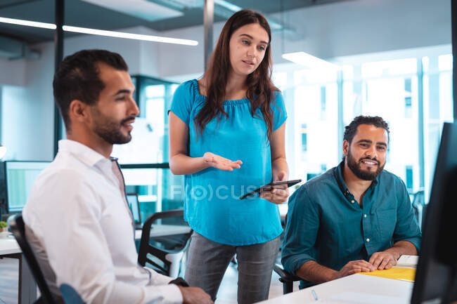 Group of diverse businesspeople discussing and using computer with colleagues in background. work at a modern office. — Stock Photo