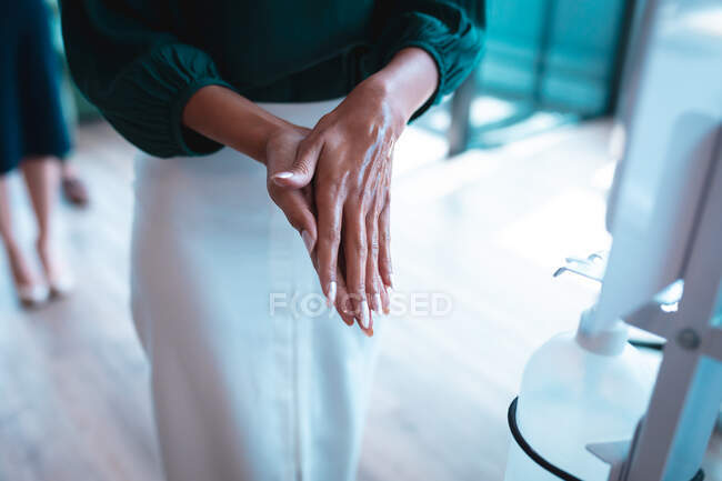 Businesswoman disinfecting hands at work. work at a modern office during covid 19 coronavirus pandemic. — Stock Photo