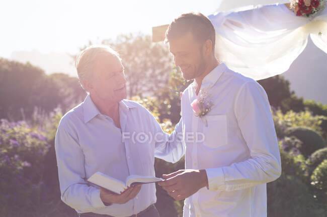 Sposo caucasico sposarsi e parlare con officiante di nozze. matrimonio estivo, matrimonio, amore e concetto di celebrazione. — Foto stock