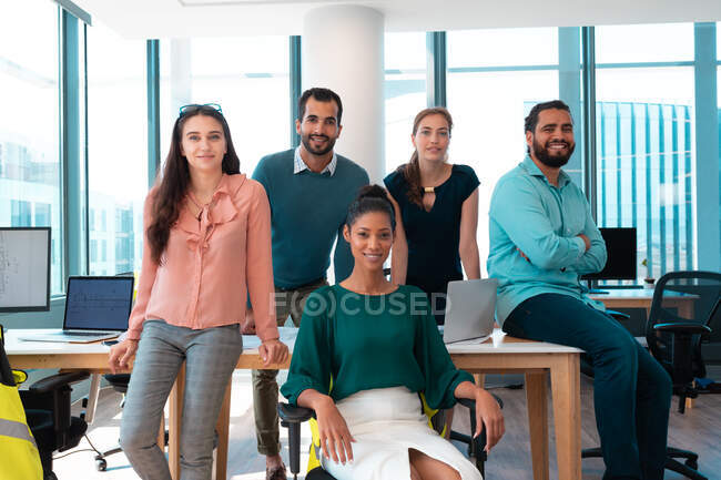 Porträt einer Gruppe unterschiedlicher Geschäftsleute, die zusammen lächeln und am Tisch sitzen. Arbeit in einem modernen Büro. — Stockfoto