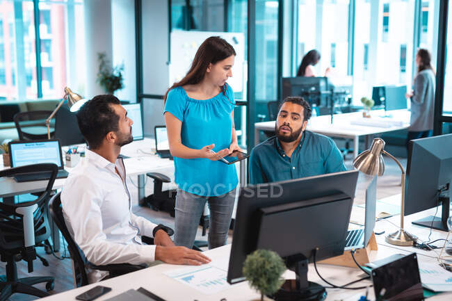 Группа бизнесменов обсуждает и использует компьютер с коллегами в фоновом режиме. работа в современном офисе. — стоковое фото