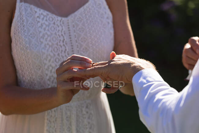 Sposi e sposi caucasici che si sposano e si mettono l'anello. matrimonio estivo, matrimonio, amore e concetto di celebrazione. — Foto stock
