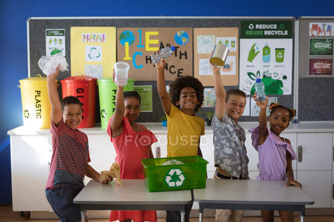 Портрет групи різноманітних студентів, які посміхаються, тримаючи рециркуляційні пластикові предмети в школі. концепція школи та освіти — стокове фото