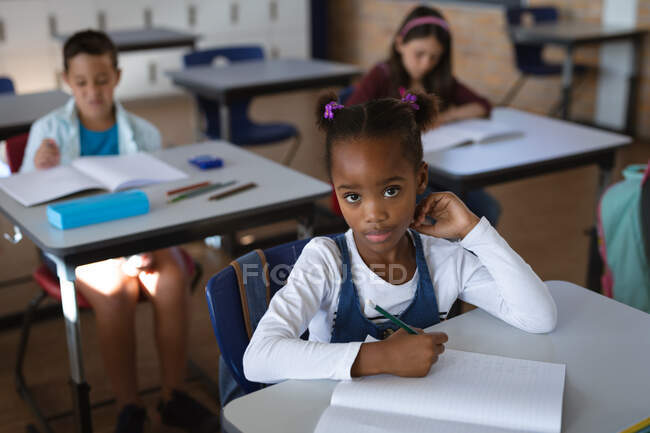 Portrait de fille afro-américaine assise sur son bureau dans la classe à l'école. concept scolaire et éducatif — Photo de stock