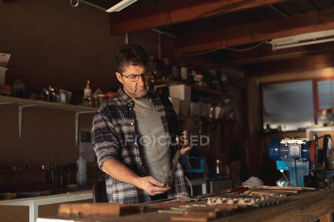 Caucasian male knife maker standing at desk, preparing knife in workshop. independent small business craftsman at work. — Stock Photo