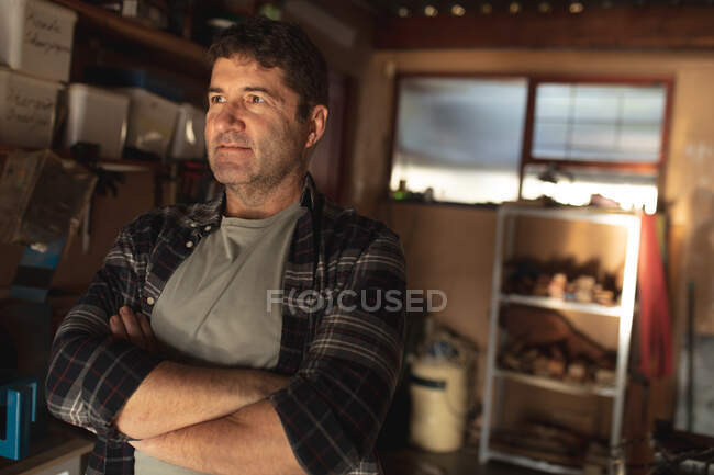 Caucasian male knife maker with crossed hands in workshop. independent small business craftsman at work. — Stock Photo