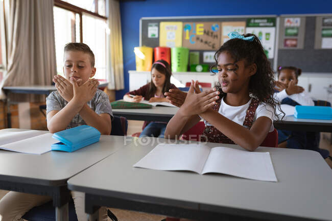Fille afro-américaine et garçon caucasien qui se parlent en langue des signes à l'école. concept scolaire et éducatif — Photo de stock