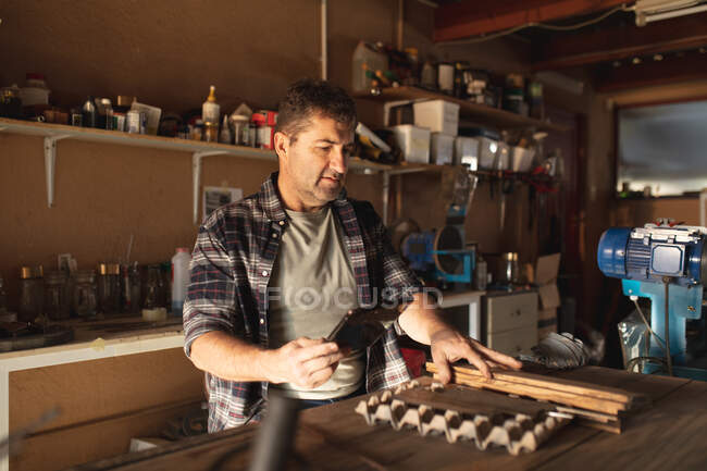 Caucasian male knife maker preparing mold, using tablet in workshop. independent small business craftsman at work. — Stock Photo